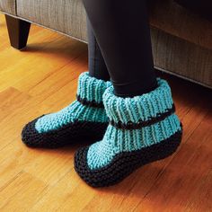 a woman's legs in knitted slippers on the floor next to a couch