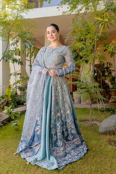 a woman in a blue gown standing on the grass