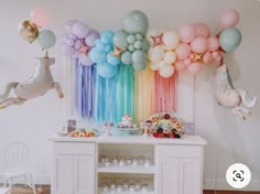 a rainbow themed birthday party with balloons, cake and cupcakes