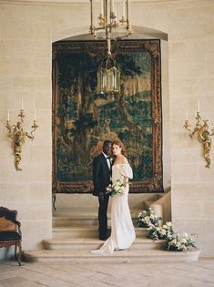 a bride and groom standing in front of an ornate painting at their wedding reception venue