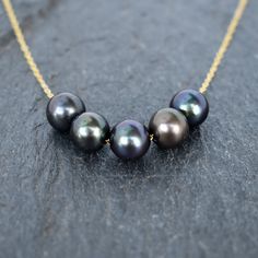 Five beautiful, lustrous black freshwater pearls move freely on the chain for a statement necklace. These pearls are very near round, approximately 9mm - 10mm in size. On your choice of gold filled or sterling silver chain. (I recommend selecting double rope chain for this necklace.) This material will not tarnish, and can even get wet! **Tones/hues may vary from one pearl to the next** Black Pearl Necklace With High Luster For Gift, Black Tahitian Pearl Jewelry With Round Beads, Black Tahitian Pearl Round Beads Jewelry, Black Tahitian Pearl Necklace With Pendant, Black Tahitian Pearl Necklaces With Round Beads, Black Tahitian Pearl Round Bead Necklaces, Black Tahitian Pearl Necklace With Round Beads, Black Tahitian Pearl Round Bead Necklace, Black Single Strand Tahitian Pearl Necklace