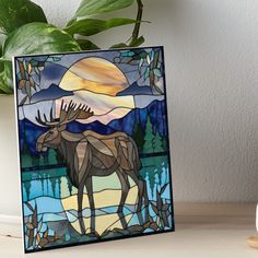 a stained glass moose standing in front of a lake at night with the sun setting behind it