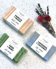 three soap bars sitting on top of a counter next to a flower and some plants