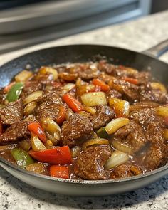 a skillet filled with beef and vegetables on top of a counter next to a microwave