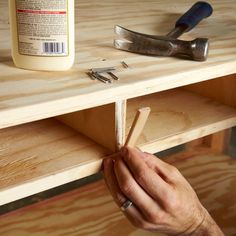 a person is working with woodworking tools on a wooden shelf next to a bottle of glue