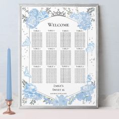 a wedding seating chart with blue flowers on it and a candle in the foreground