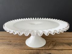 a white cake plate sitting on top of a wooden table