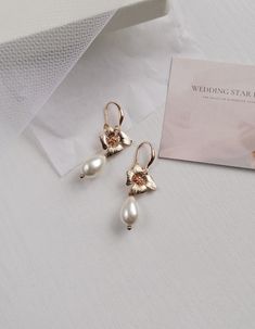 The classic version of earrings in gold steel is a wonderful minimalistic addition to a wedding look. Large beige drop-shaped pearls are complemented by a small golden flower. Earrings length 4 cm. Details: - Add to the hairstyle only after it is completely ready. - Do not expose accessories to detergent or hairspray. - Store accessories in a dry place, away from direct sunlight and moisture. - Designed and made in Poland. - The accessory will be packed in a gift box. If you have any questions, Dangle Flower Earrings, Drop Pearl Earrings, Earrings Dangling, Pearls Earrings, Golden Flower, Wedding Accessory, Minimal Wedding, Wedding Jewelry Earrings, Earrings In Gold