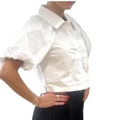 A sleek cotton poplin top with a tapered button up front and bubble sleeves. Its slightly cropped length and boxy fit make it a versatile piece for any occasion. Elevate your wardrobe with this fashion-forward must-have. Slightly cropped Button up closure Length: 17.5" 100% cotton Hand wash Chic Collared Poplin Blouse, Trendy Relaxed Fit Puff Sleeve Top For Work, Fitted Button-up Crop Top For Work, Chic Button-up Cropped Shirt With Button Closure, Classic Cropped Shirt For Office, Daywear Poplin Tops With Button Closure, Poplin Tops With Button Closure For Daywear, Daywear Tops With Button Closure, Chic Button-up Poplin Blouse