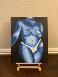 a painting of a naked woman on a wooden easel