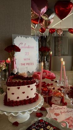 a table topped with a cake and lots of hearts on top of it next to candles