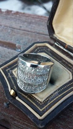 a silver ring sitting on top of a wooden table next to an open case filled with jewelry