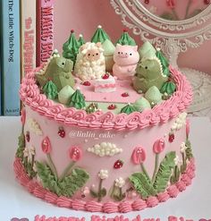 a birthday cake decorated with pink icing and green decorations, including two little pigs