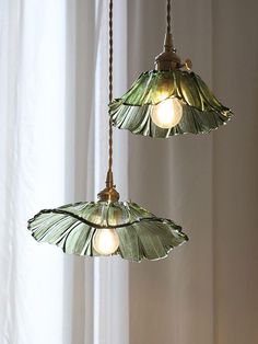 two green glass lamps hanging from a ceiling