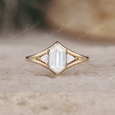 a gold ring with an emerald cut diamond in the center on top of a table