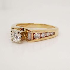 a yellow gold ring with two diamonds on the side and a white diamond in the middle