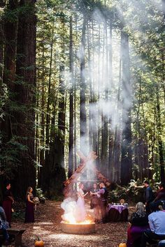 a group of people sitting around a fire pit in the woods