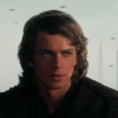 a young man with long hair and blue eyes stares into the distance in star wars