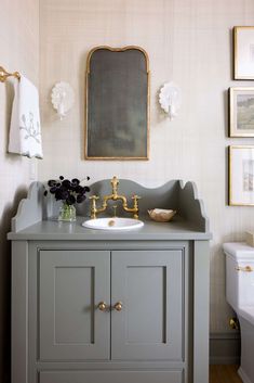 a bathroom with a sink, mirror and pictures hanging on the wall above it's vanity