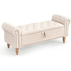 an upholstered bench with wooden legs and buttons on the back, in white linen