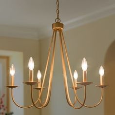 a chandelier hanging from the ceiling in a room with white walls and wood flooring