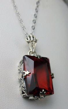 "Simulated Red Ruby Pendant & Earrings GL Design#15 Custom Made Pendant (P15) This is an Art Deco style sterling silver filigree 10 carat Simulated/man-made red ruby pendant necklace. The beautiful rectangle-cut ruby gem is 16mm x 12mm. The 1.5mm necklace chain (if chosen) is adjustable from 18\"-20\". The entire pendant is 1 1/8\" long by 9/16\" wide. Notice the beautiful craftsmanship of the silver Art Deco filigree bail. The earrings are 16mm x 12mm each and 1 5/16\" long. The dazzling ge Classic Red Jewelry As A Gift, Formal Hallmarked Pendant Jewelry, Exquisite Ruby Pendant Jewelry, Ruby Pendant Jewelry For Valentine's Day, Victorian Pendant Jewelry For Formal Occasions, Unique Ruby Gemstone Jewelry, Formal Ruby Jewelry With Faceted Details, Fine Gemstone Jewelry For Valentine's Day, Fine Jewelry Gemstone For Valentine's Day