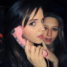 two young women are talking on the telephone