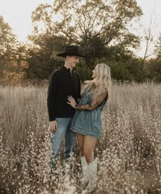 a man and woman standing in tall grass