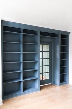 an empty room with blue bookshelves and wooden floors