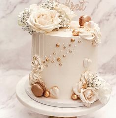 there is a white cake with gold decorations on the top and flowers on the bottom