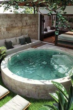 an outdoor hot tub in the middle of a patio with couches and tables around it