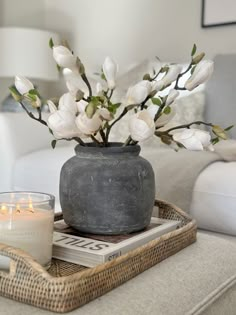 a vase with white flowers sitting on top of a tray next to a candle