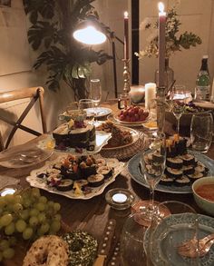 a table filled with plates and bowls of food next to candles on top of a wooden table