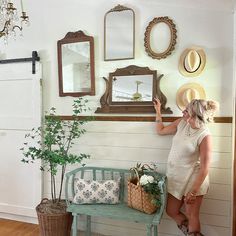 a woman standing next to a bench in front of a wall with pictures on it