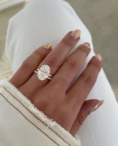 a woman's hand with a diamond ring on top of her finger and white gloves