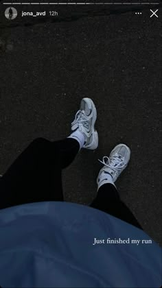 two white tennis shoes sitting on top of a blue tarp next to a person's feet