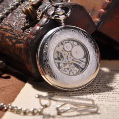 This Silver Shield Full Hunter Pocket Watch is carefully crafted to perfection. The cover is intricately designed with a subtle striped pattern and room for engraving personal initials, making it the perfect gift for any occasion. The crystal face and back cover brilliantly showcases the skeleton and mechanics of the clock's inner workings, giving it an antique feel that any pocket watch lover would enjoy. A Full Hunter Pocket Watch is a classic style that includes a pocket watch cover that enti Luxury Classic Silver Pocket Watch, Luxury Silver Pocket Watch With Chronometer, Roman Antique, Plexiglass Mirror, Interlocking Pattern, Scottish Tweed, Gold Pocket Watch, Handstamped Bracelet, Stamped Bracelet