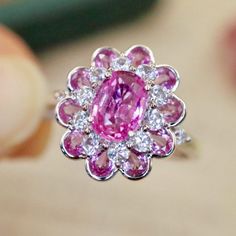 a pink and white diamond ring being held by someone