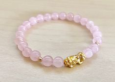 This is Pure Real 24 Karat Gold Pixiu/Natural Rose quartz / real 14k gold beads Real Gold Pixiu - Approximately 13mm x 6mm ( hollow , less than 1 g ) 14 karat Gold Beads Round - Approximately 3mm Natural Rose quartz - Approximately 6mm Hallmark/Stamp 999 for 24k Gold (PIXIU) Please select bracelet size. All are handmade with care .Strung on heavy duty stretchy/elastic. Products and photo may differ/beads color may vary. Bracelet Comes with Storage Bag & Box PIXIU/PIYAO ~ Secures Wealth and G Gold Bracelets With Rose Quartz And Natural Stones, Elegant Gold Bracelets With Rose Quartz, Elegant Gold Crystal Bracelet For Meditation, Elegant Gold Rose Quartz Bracelets, Elegant Rose Quartz Gold Bracelets, Gold Beaded Bracelet With Rose Quartz Round Beads, Gold Beaded Bracelets With Rose Quartz Round Beads, Gold Beaded Bracelets With Rose Quartz, Gold Rose Quartz Beaded Bracelets With Round Beads