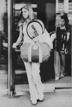 a woman carrying a large bag while standing in front of a building