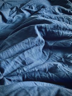 an unmade bed with blue linens and sheets on top of eachother