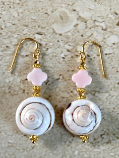 Shiva Eye Shell Earrings featuring a 25MM natural pink shiva eye shell accented with a 10MM clover shape pink queen conch stone and 3MM gold crystals.  Gold filled ear wires.  Earrings measure 1 1/2 inches and are handmade. Pink Dangle Jewelry For Vacation, Handmade Pink Shell-shaped Jewelry, Handmade Pink Shell Jewelry, Pink Dangle Earrings For Beach, Bohemian Shell-shaped Pink Jewelry, Pink Beach Jewelry With Matching Earrings, Bohemian Pink Shell-shaped Jewelry, Pink Jewelry With Matching Earrings For Beach, Handmade Pink Spiritual Earrings