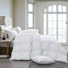 a large white bed with pillows on top of it in a room next to a window