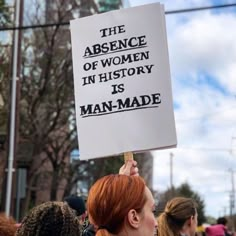 a woman holding up a sign that says the presence of women in history is man - made