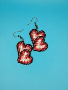 two red heart shaped beaded earrings on a blue background