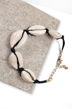 a bracelet with seashells on it is sitting on a tile floor next to a keychain