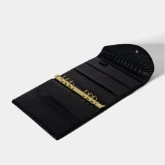 a black alligator skin wallet with gold hardware and keys on the front, open to show it's contents