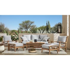 an outdoor living room with furniture and cactus in the background