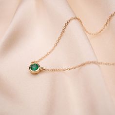 Our 14k Emerald Bezel Necklace features a lustrous bright, and ethically-sourced genuine emerald. This necklace is ideal for layering but easily a statement when worn on its own. 14k Gold and genuine Zambian Emerald Approximately .55 CTW 5.2mm stone dimension 14k Cable Chain Available in lengths 16" and 18" Due to the handmade nature of this necklace, please allow 1 - 3 weeks for processing. Fine Emerald Necklaces With Bezel Setting, Classic Emerald Necklaces With Bezel Setting, Green Necklace With Bezel Setting For May Birthstone, Emerald Necklace With Delicate Yellow Gold Chain, Emerald Necklace With Bezel Setting For Anniversary, Yellow Gold Emerald Necklace With Delicate Chain, Dainty Emerald Necklace For Formal Occasions In May, Anniversary Emerald Necklace With Bezel Setting, Delicate Yellow Gold Emerald Necklace