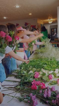 several people are arranging flowers on a table